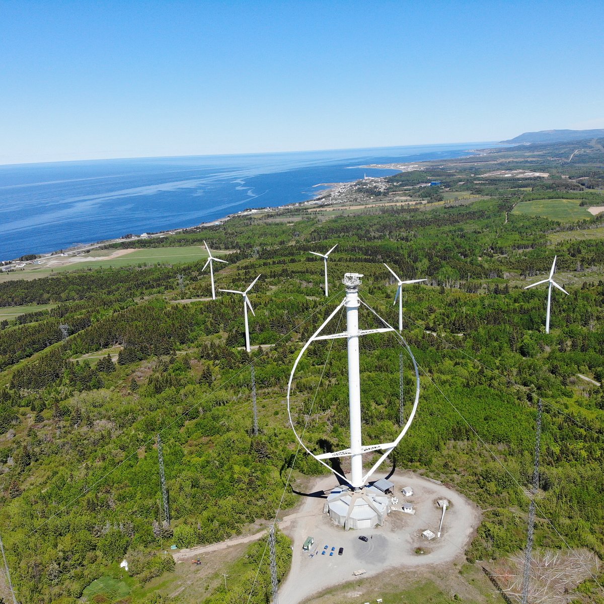 Projet Éole à Cap-Chat en Gaspésie, Québec, montrant des éoliennes modernes dans un paysage côtier verdoyant. Initiative d'énergie renouvelable avec vue sur la mer.